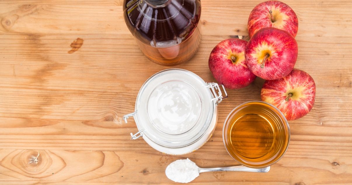 Imagen senital de una mesa de madera sobre la que se apoyaron manzanas miel y kefir como fuente de prebioticos y probioticos