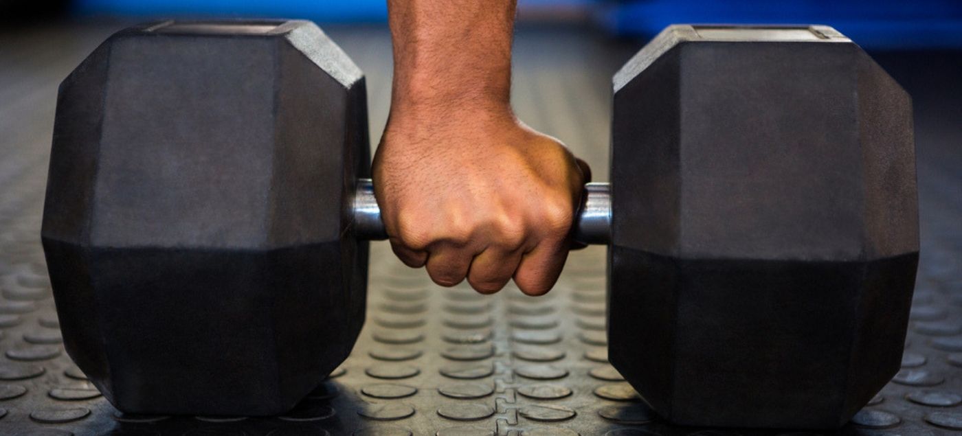 Zoom a una pesa, elemento esencial en la rutina de un hombre joven que como hobbie asiste al gimnasio y quiere ganar masa muscular (1)